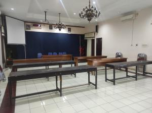 a conference room with wooden tables and a projection screen at Capital O 93024 Hotel Ganesha in Purworejo