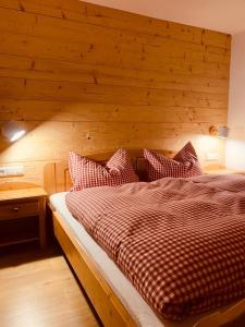 1 dormitorio con 1 cama y pared de madera en Gästehaus Steiert Fewo Kuhbergblick en Lenzkirch