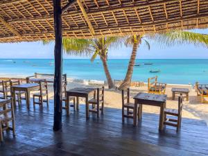 a restaurant on the beach with tables and chairs at Kibanda Lodge and Beach Club in Nungwi