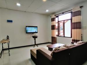 a living room with a couch and a flat screen tv at Highway Twin Home East wing in Kadawatha