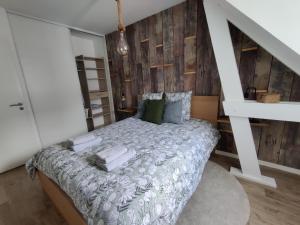 - une chambre avec un lit et un mur en bois dans l'établissement Appartement NATURA 2 chambres, à Vitré