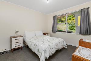 a bedroom with a bed and a window at Knights Retreat - Paihia Holiday Home in Paihia