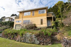 a house on a hill with a stone wall at Knights Retreat - Paihia Holiday Home in Paihia