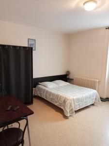 Un dormitorio con una cama y una mesa. en Hôtel Restaurant de la Gare (Studios Du Breuil) en La Roche-Posay