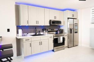 La cuisine est équipée de placards blancs et d'un réfrigérateur en acier inoxydable. dans l'établissement Live in style! apartment, à North Miami Beach