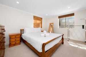 a white bedroom with a large bed and a window at Rosie's in Woody Point