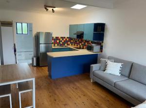 eine Küche mit einem Sofa und einem Kühlschrank in einem Zimmer in der Unterkunft Copacabana 4 61 Sandy Point Rd - water views, air con and WiFi in Corlette