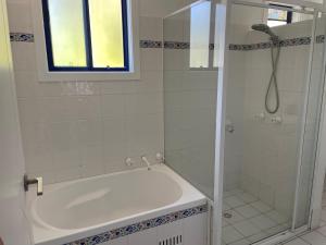 ein Badezimmer mit einer Dusche und einer weißen Badewanne in der Unterkunft Copacabana 4 61 Sandy Point Rd - water views, air con and WiFi in Corlette