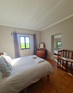 Un dormitorio con una gran cama blanca y una ventana en Die Blouhuis Farmhouse Retreat with a hot tub en Cloeteskraal