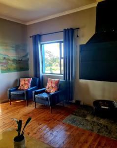 una sala de estar con 2 sillas azules y una ventana en Die Blouhuis Farmhouse Retreat with a hot tub en Cloeteskraal