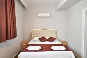 RED MOON SUITES في فتحية: غرفة نوم بسرير وملاءات بيضاء وستائر حمراء