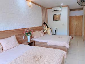 una mujer parada en una habitación de hotel con 2 camas en Phương Đông Hotel, en Sầm Sơn