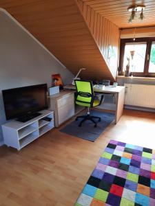 een zolderkantoor met een bureau en een groene stoel bij Ferienwohnung Weingarten 