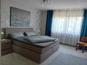 a bedroom with a large bed with blue curtains at Ferienwohnung Margit in Sulzfeld (im Grabfeld)