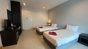 um quarto de hotel com duas camas e uma televisão em Karon Sea Side em Praia de Karon