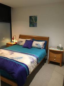 a bedroom with a bed with purple sheets and a night stand at South Yarra 1Br Apartment in Melbourne