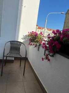 una silla sentada en un balcón con flores en Grunwaldzki24 Apartments - FREE PARKING - OLD TOWN, CENTRUM, en Wroclaw
