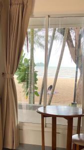 una mesa y una ventana con vistas a la playa en Laemsing Natural Beach Resort en Ban Pak Nam
