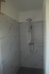 y baño con ducha y paredes de mármol blanco. en Ferienhaus Masser, 