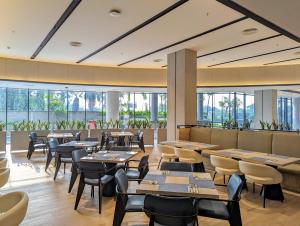 un restaurante con mesas, sillas y ventanas en Fairfield by Marriott Jakarta Soekarno-Hatta Airport en Tangerang