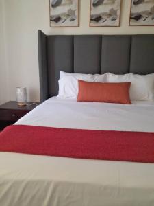 a large white bed with a red pillow on it at Ambré Guesthouse in Francistown