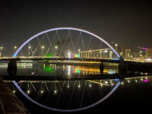 een brug over een waterlichaam 's nachts bij Glasgow SECC Hydro River View in Glasgow