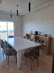 una sala da pranzo con tavolo e sedie bianchi di vacance et confort les sablettes a Mohammedia