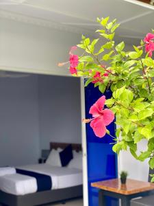 迪古拉的住宿－Tides Dhigurah，一间卧室配有床和种有粉红色花卉的植物