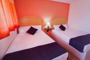 瓜納華托的住宿－Hotel Casa 12 Reales Guanajuato，配有红色墙壁的小客房内的两张床