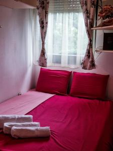a bedroom with a bed with red pillows and a window at Boulevard Apartments in Kumanovo