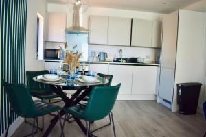 eine Küche mit einem Esstisch und grünen Stühlen in der Unterkunft R V Properties Luxury Suites 21 & 23 in Hemel Hempstead