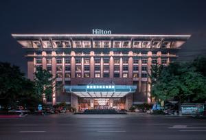 un edificio iluminado con un cartel de hilton por la noche en Hilton Xi'an, en Xi'an