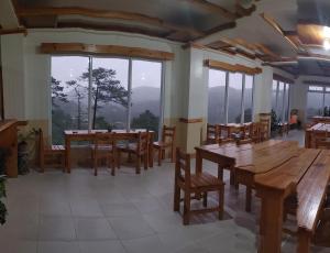 un comedor con mesas y sillas de madera y ventanas en Cam-Jhao's Homestay en Sagada