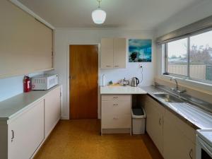 a kitchen with white cabinets and a sink and a window at High Country Cottage in Twizel