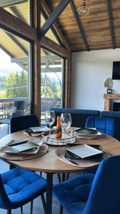 a wooden table with glasses and napkins and blue chairs at Tiny House Todireni in Vatra Dornei