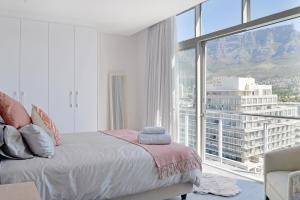 ケープタウンにあるNaomi - Designer Penthouse in the Heart of Cape Townのベッドと大きな窓のある寝室