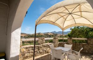 un patio con sombrilla, mesa y sillas en Casa rural el Carmen, en Prado del Rey