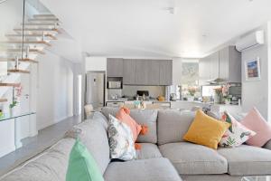 ケープタウンにあるNaomi - Designer Penthouse in the Heart of Cape Townのカラフルな枕が置かれた灰色のソファのあるリビングルーム