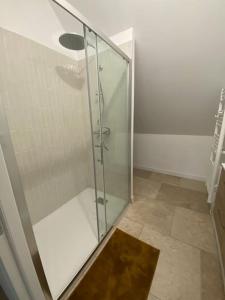 a glass shower in a bathroom with a tile floor at Domaine de La Quenouille - Appartement B in Péronne