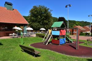 een park met een speeltuin met een glijbaan en een bank bij La Petite Fecht in Munster