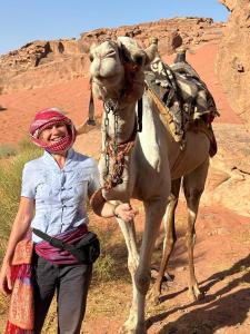 Una mujer parada junto a un camello en el desierto en Bedouin Holidays Camp and Jeep Tours, en Wadi Rum