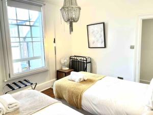 a bedroom with two beds and a chandelier at EMMANUEL HOUSE LOVELY 1 - BEDROOM APT IN HISTORICAL BUILDING CENTRAL CAMBRIDGE in Cambridge