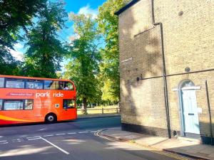 a red double decker bus parked next to a brick building at EMMANUEL HOUSE LOVELY 1 - BEDROOM APT IN HISTORICAL BUILDING CENTRAL CAMBRIDGE in Cambridge