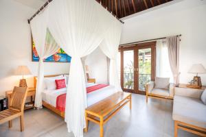 1 dormitorio con cama con dosel y sofá en Prabhu Ubud Villa, en Ubud