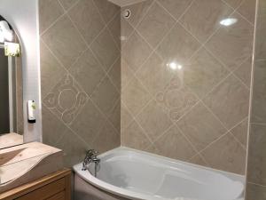 a bathroom with a bath tub and a sink at Hotel Restaurant Herard in Bourbonne-les-Bains