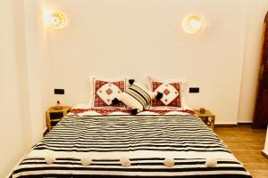a bedroom with a bed with black and white pillows at TRAVEL SURF NATURE in Tamraght Ouzdar