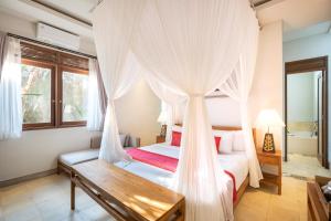 a bedroom with a bed with a mosquito net at Prabhu Ubud Villa in Ubud