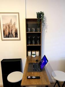 um computador portátil sentado numa secretária de madeira com dois bancos em studio très agréable em Roubaix