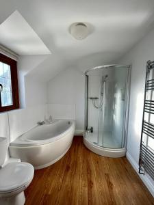a white bathroom with a tub and a toilet at Beautiful Large 4 bedroom house with hot tub in West Coker +21 photos