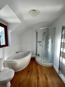 a white bathroom with a tub and a toilet at Beautiful Large 4 bedroom house with hot tub in West Coker